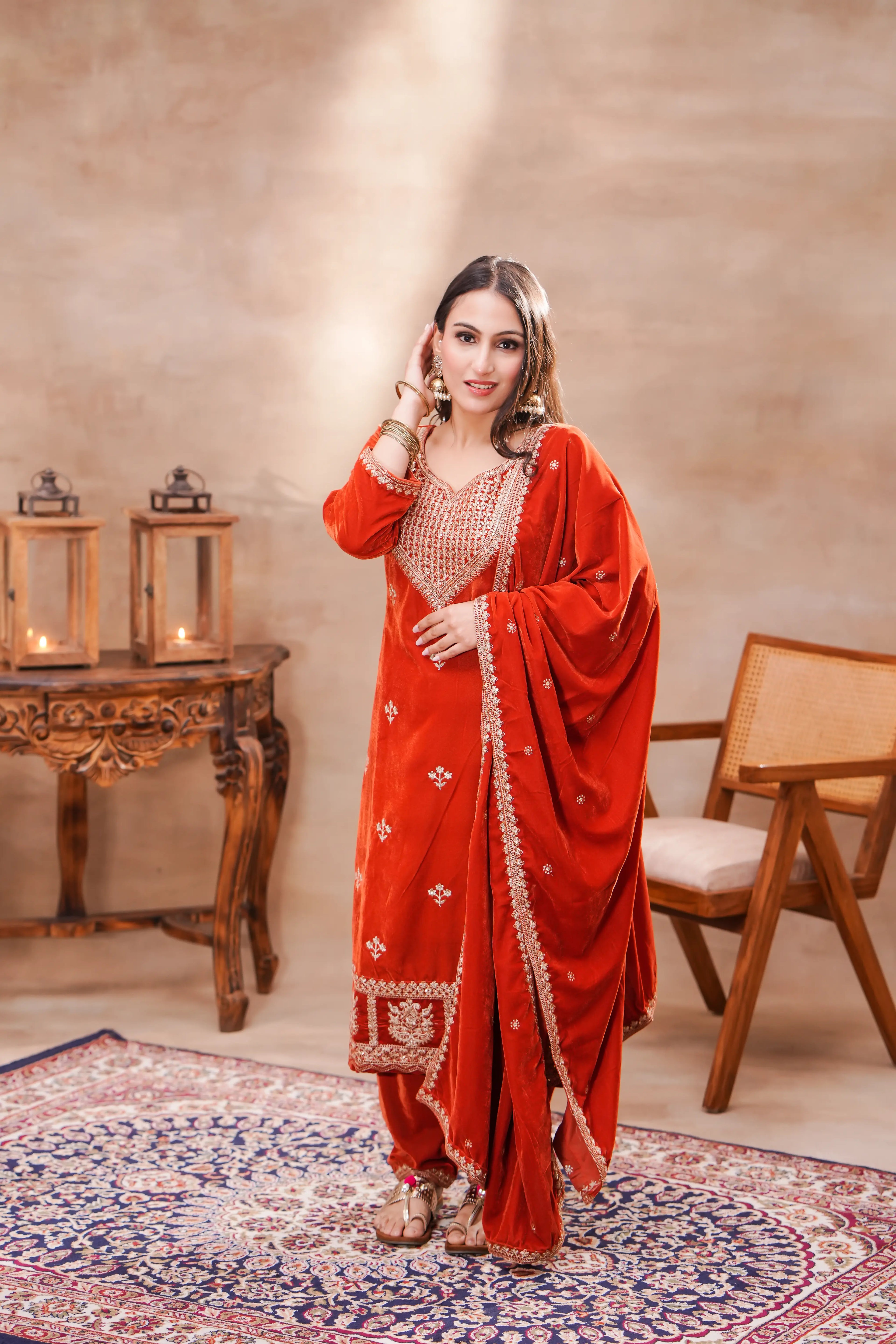 Rust-orange velvet embroidered suit set by Shuchi Man featuring a kurta, matching pants, and a draped dupatta.
